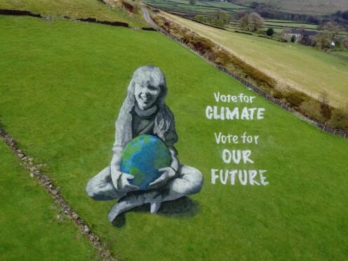 A huge anamorphic painting of a girl holding the Earth has been created in the West Yorkshire countryside to mark Earth Day (Richard McCarthy/PA)
