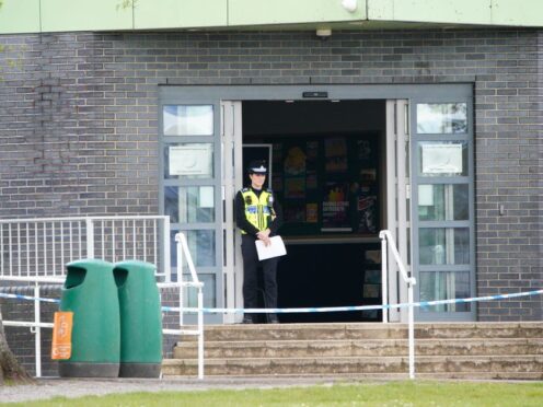 A police officer stands at the entrance to Amman Valley School, in Ammanford, Carmarthenshire (Ben Birchall/PA)