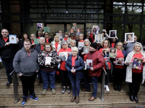Members of Northern Ireland Covid-19 Bereaved Families for Justice stand together holding images of their loved ones outside the Clayton Hotel in Belfast (Liam McBurney/PA)