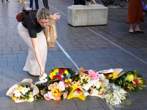 A woman brings flowers to an impromptu memorial at Bondi Junction in Sydney (Rick Rycroft/AP)