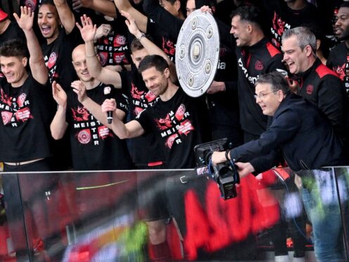 Coach Xabi Alonso, centre, and Bayer Leverkusen raise the Bundesliga trophy (David Inderlied/dpa via AP)