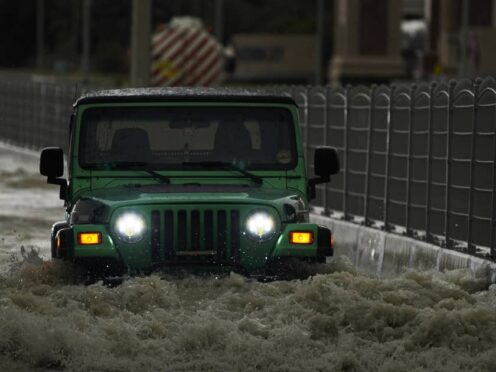 An SUV passes through water in Dubai (Jon Gambrell/AP)