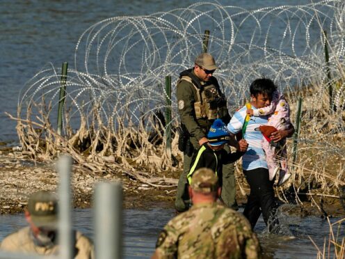 Migrants are taken into custody by officials at the Texas-Mexico border (Eric Gay/PA)