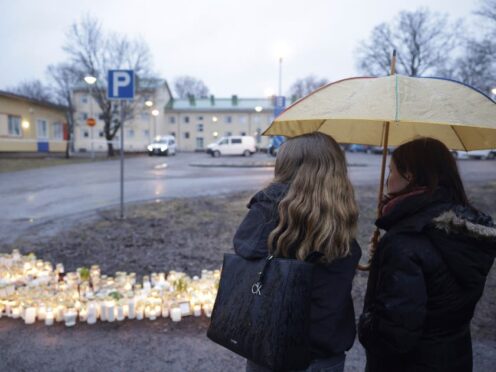 People bring candles and flowers at the school in Finland (Roni Rekomaa/Lehtikuva via AP)