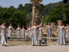Actress Mary Mina, playing a priestess, holds a torch with the flame during the final dress rehearsal of the flame lighting ceremony for the Paris Olympics, at the Ancient Olympia site in Greece (Thanassis Stavrakis/AP)