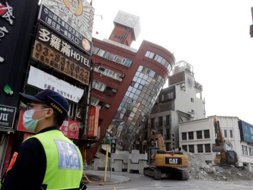 A police officer stands guard near a partially collapsed building a day after a powerful earthquake struck in Hualien City, eastern Taiwan (Chiang Ying-ying/AP)