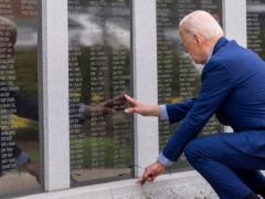 President Joe Biden reaches to touch the name of his uncle Ambrose J Finnegan Jr, on a wall at a Scranton war memorial (Alex Brandon/AP)