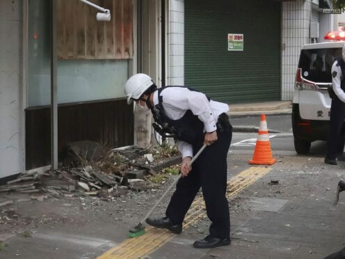 Police officers clean debris from an earthquake in Uwajima, western Japan (AP)