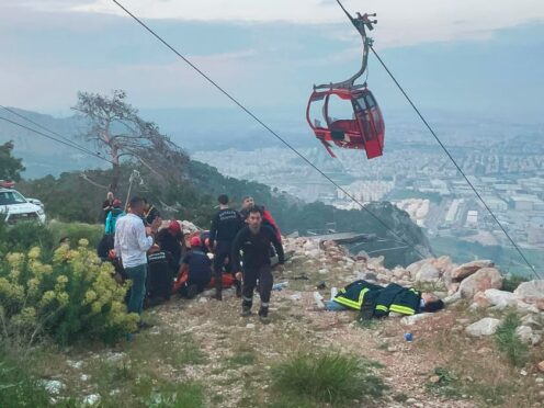 Rescue and emergency team members work with passengers of a cable car (Dia Images via AP)