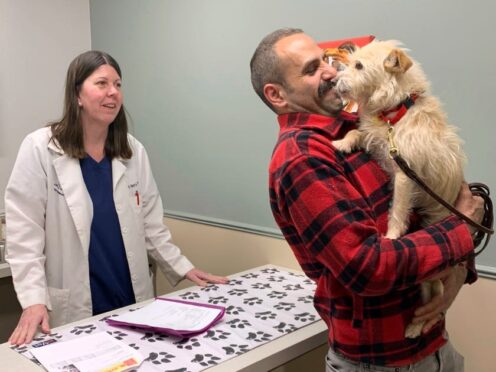 Mehrad Houman holds his dog Mishka after she was examined by veterinarian Nancy Pillsbury in Harper Woods, Michigan (Corinne Martin via AP)