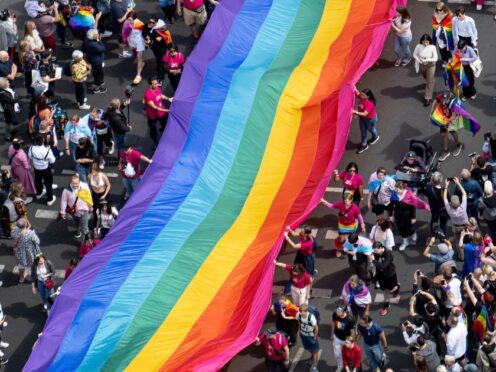 People hold a rainbow flag as they attend the 45th Berlin Pride Parade for Christopher Street Day (CSD) in Berlin (Fabian Sommer/AP)