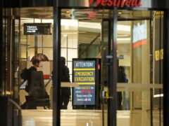 Police officers walk past a sign at Westfield Shopping Centre, where multiple people were stabbed in Sydney on Saturday (Rick Rycroft/PA)