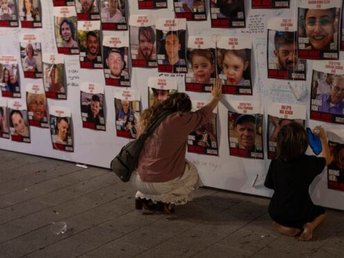 A woman touches photos of Israelis missing and held captive in Gaza, displayed on a wall in Tel Aviv (Petros Giannakouris/AP)