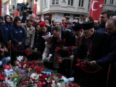Representatives of the Turkish communities put flowers over a memorial placed on the spot of an explosion on Istanbul’s popular pedestrian Istiklal Avenue in 2022 (Khalil Hamra/AP)