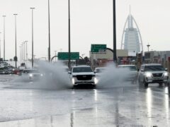 An SUV splashes through standing water on a road in Dubai (Jon Gambrell/AP)
