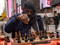 Tunde Onakoya, 29, a Nigerian chess champion and child education advocate, playing in Times Square in New York (Yuki Iwamura/AP)
