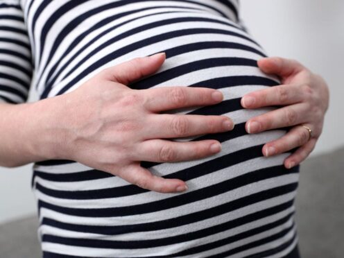 A pregnant woman holds her stomach (Andrew Matthews/PA)