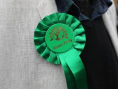 A person wearing a Green Party rosette (PA)
