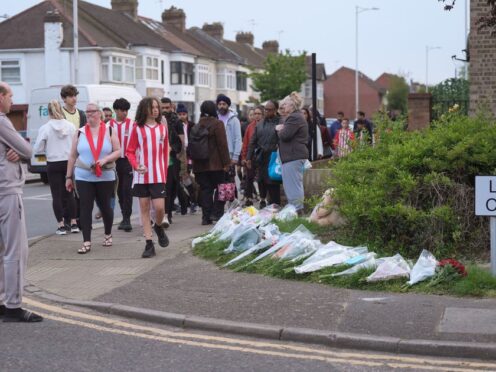 Members of the community looking at floral tributes in Hainault, north east London (Yui Mok/PA)