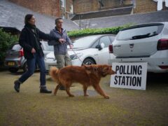 Cinna, an eight-year-old rescue dog from Greece, arrives with its owners at the polling station at St Alban’s Church, south London (PA)