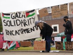 A student adjusts a sign at an encampment on the grounds of Newcastle University, protesting against the war in Gaza (Owen Humphreys/PA)