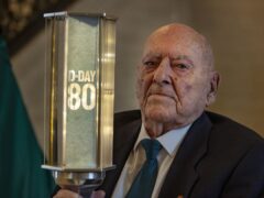 Veteran George Horner holds the D-Day 80 torch of commemoration in the Great Hall at Parliament Buildings at Stormont (Liam McBurney/PA)