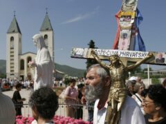 Pilgrims walk around a statue of the Blessed Virgin Mary near the church of St James in Medjugorje, Bosnia and Herzegovina (Amel Emric/AP)