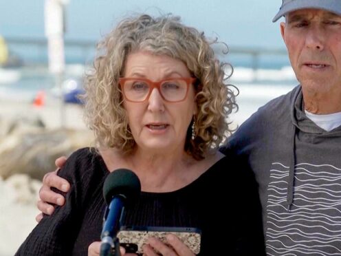 In this image taken from video, Australia’s Debra Robinson with her husband Martin, address the media on the beach in San Diego (Channel 9/POOL via AP)
