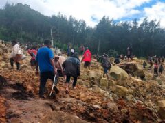 People cross over the landslide debris as they seek safety (Benjamin Sipa/International Organisation for Migration/AP)