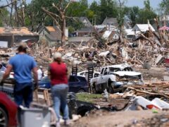 People survey a tornado damaged neighbourhood (Charlie Neibergall/AP)