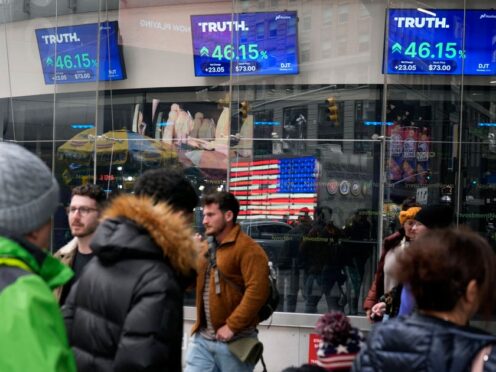Pedestrians walk past the Nasdaq building as the stock price of Trump Media & Technology Group Corp is displayed on screens in March (Frank Franklin/AP)
