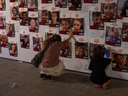 A woman touches photos of Israelis missing and held captive in Gaza (Petros Giannakouris/AP)