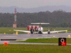 In this image taken from video, passengers alight after a light plane with three people aboard landed safely without landing gear at Newcastle Airport, Australia (Channel 10 via AP)