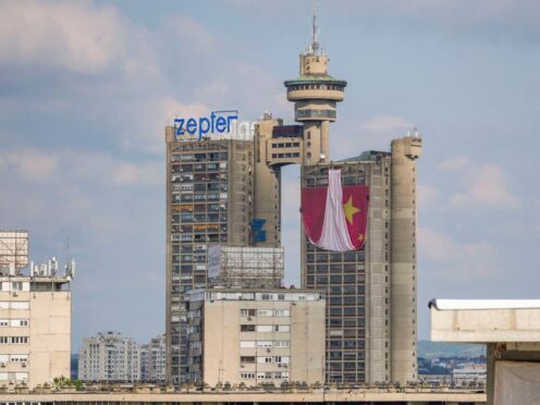 Workers hang on ropes to install a giant Chinese national flag on a skyscraper that is a symbolic gateway leading into the city from the airport, in Belgrade, Serbia (Darko Vojinovic/AP)