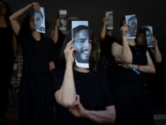 Relatives and supporters of Israeli hostages held by Hamas in Gaza hold photos of their loved ones during a performance calling for their return in Tel Aviv (AP)