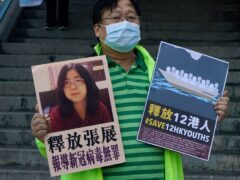A pro-democracy activist holds placards with the picture of Chinese citizen journalist Zhang Zhan outside the Chinese central government’s liaison office, in Hong Kong (Kin Cheung/AP)