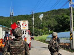 Balloons with rubbish believed to have been sent by North Korea hang on electric wires as South Korean army soldiers stand guard in Muju, South Korea (Jeonbuk Fire Headquarters via AP)