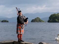 Lone bagpiper Richard Cowie, from the Cumbria Freemasons, warms up his pipes ahead of playing on the deck of one of Windermere Lake Cruises traditional steamers at Bowness-on-Windermere, Lake District, during a D-Day commemoration event (Danny Lawson/PA)