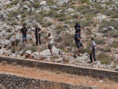 A search team scours a rocky area on Symi, Greece (Yui Mok/PA)
