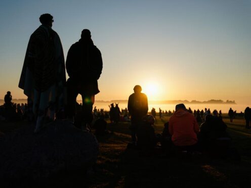 People watch the sun rise as they take part in the summer solstice at Stonehenge in Wiltshire (Andrew Matthews/PA)
