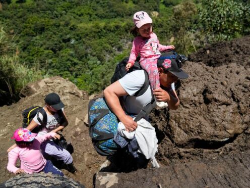 Residents cross landslide-affected terrain in Banos, Ecuador (Dolores Ochoa/AP)