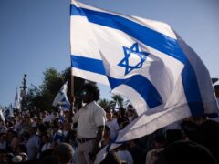 Israelis wave national flags during the march (Leo Correa/AP)