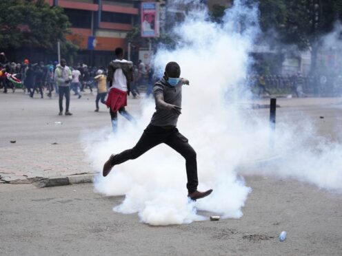 A man kicks back a tear gas grenade towards Kenyan anti-riot police during a protest over proposed tax hikes in a finance Bill in Nairobi (Brian Inganga/AP)