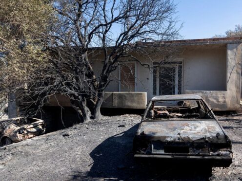 A burned out car is seen in the yard of a house after a wildfire at Keratea area, south east of Athens (AP Photo/Yorgos Karahalis)