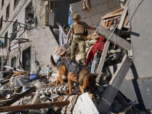 A rescue worker with a dog searches for victims in a damaged apartment building after it was hit by Russian air bomb in Kharkiv, Ukraine, on Saturday (Andrii Marienko/AP)