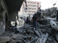 Palestinians stand on the rubble of a building bombed by Israel in the Nuseirat refugee camp, Gaza Strip (Jehad Alshrafi/AP)