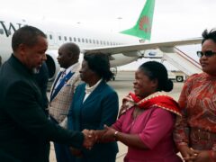 Saulos Chilima, left, greets government officials at Lillongwe airport (AP)