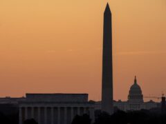The sky glows orange as the sun rises near the US Capitol, Washington Monument and Lincoln Memorial in Washington (Alex Brandon/AP)
