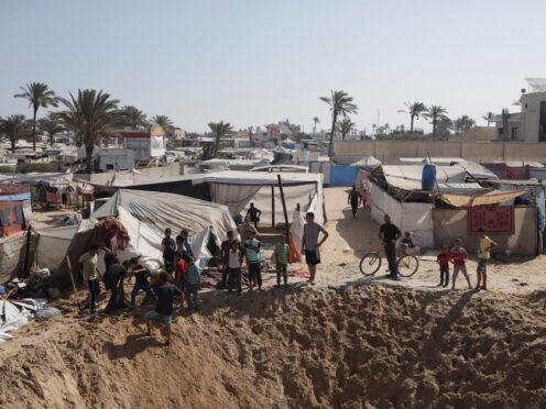 Palestinians gather at the edge of a crater after an Israeli airstrike (Jehad Alshrafi/AP)