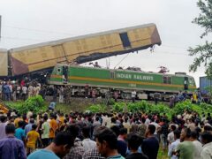 Onlookers watch as rescuers work after a cargo train rammed into Kanchanjunga Express, a passenger train, near New Jalpaiguri station, West Bengal state, India (Diptendu Dutta/AP)